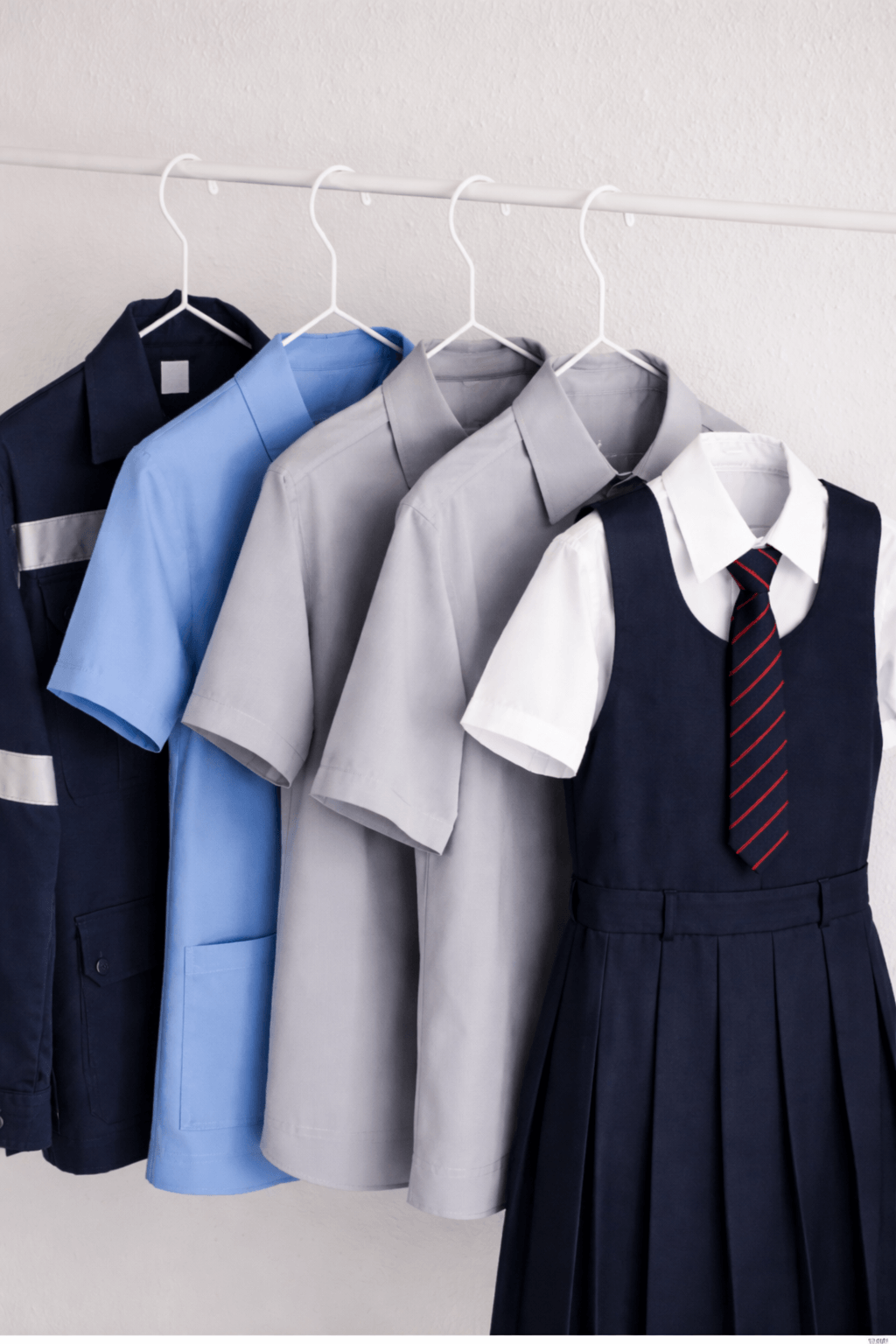 Several tailored uniform shirts hanging elegantly on a rack
